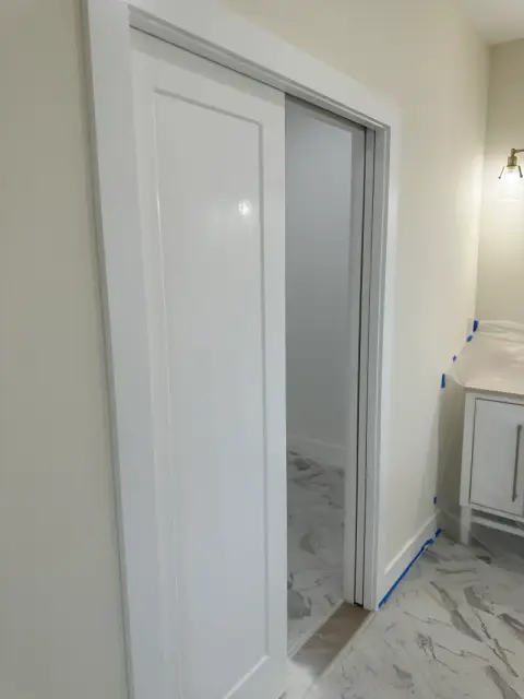 White pocket door with clean trim beside a bathroom entrance