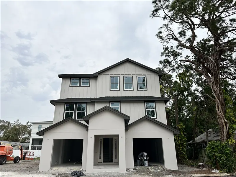 Three-story home with gray board-and-batten siding and dark trim after exterior painting