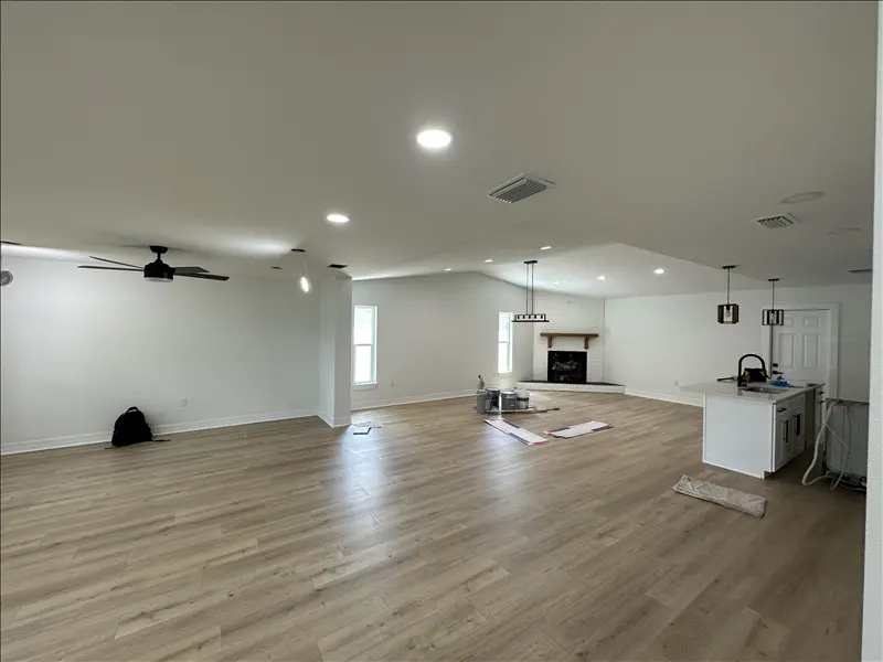 Open-concept living room and kitchen with smooth freshly painted white walls and recessed lighting
