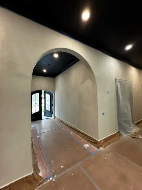 Arched doorway and limewash walls leading to black double entry doors