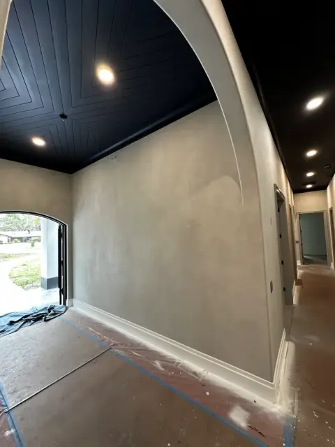 Wide limewash wall beside an arched opening with white baseboards