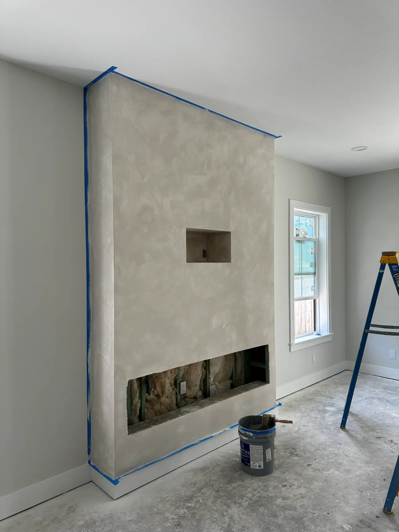Limewash fireplace wall with painter's tape along the edges during the project