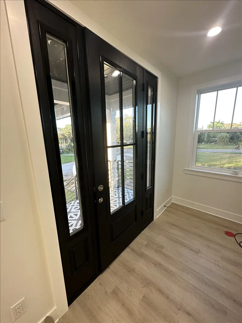 Black-painted glass entry doors with clean white trim and baseboards